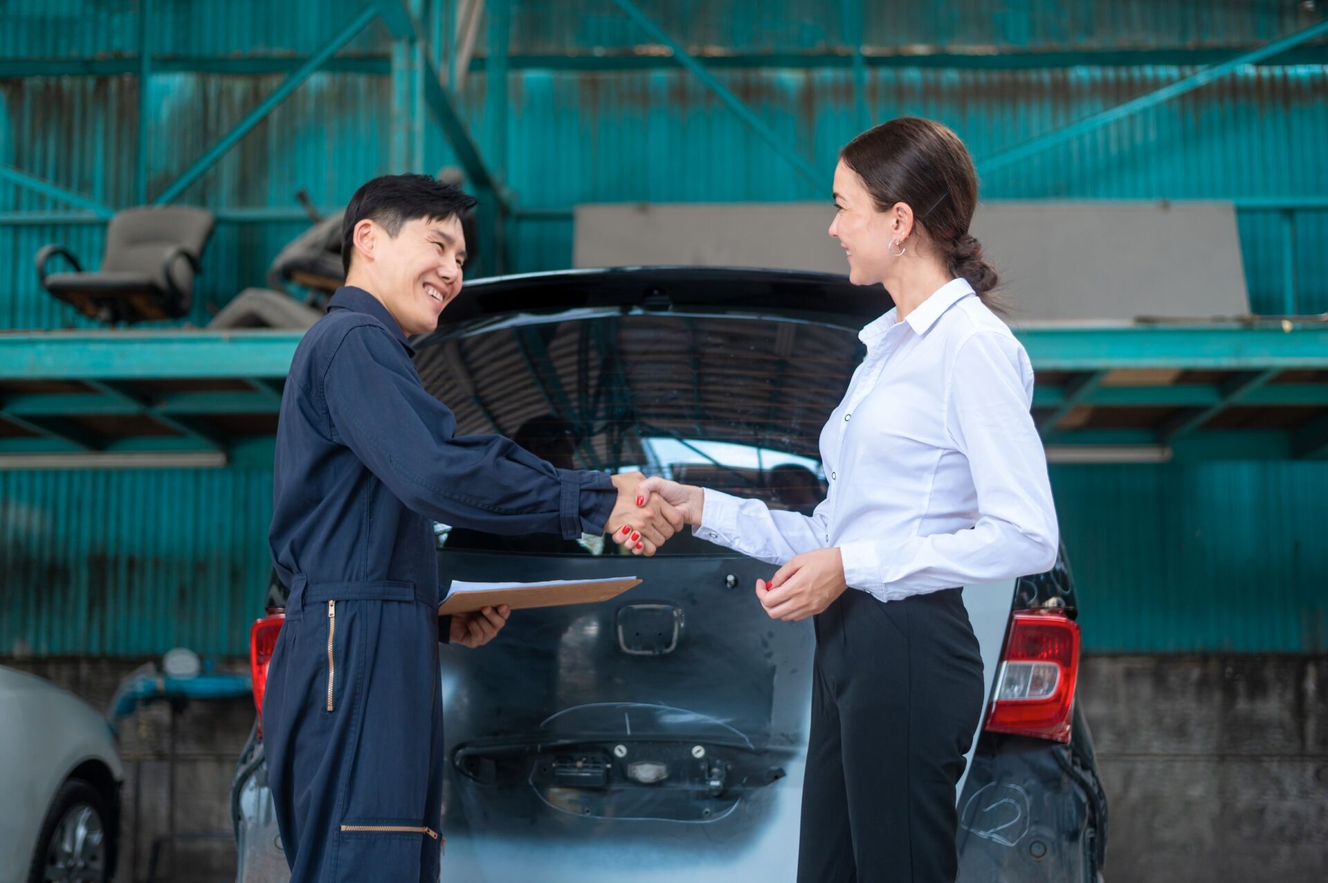 A young Caucasian woman shaking hand with mechanic man feeling happy about repair service