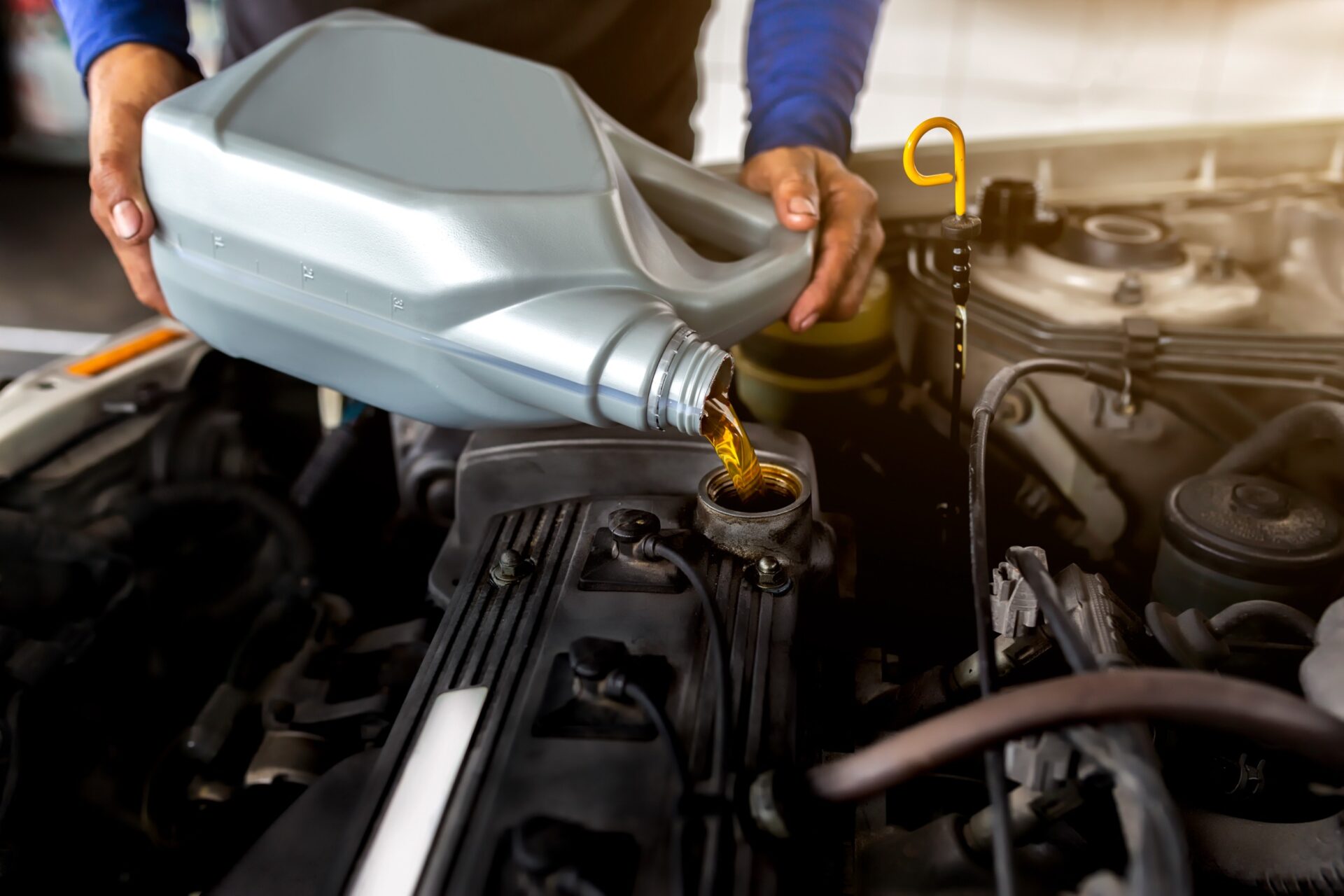 Car mechanic replacing and pouring fresh oil into engine at maintenance repair service station